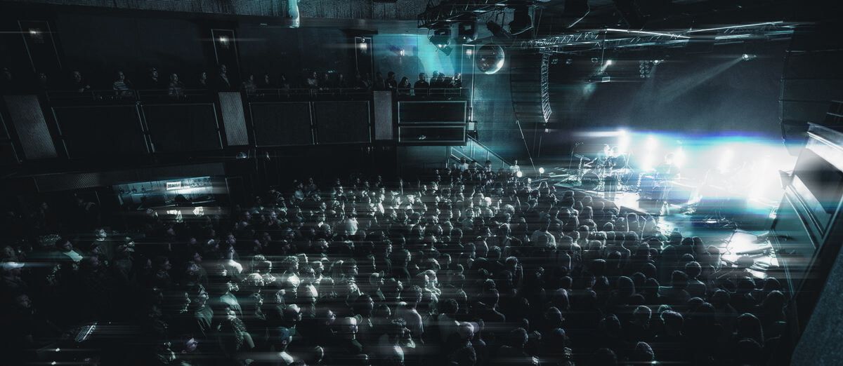 A full room at The Pearl facing a stage washed in light